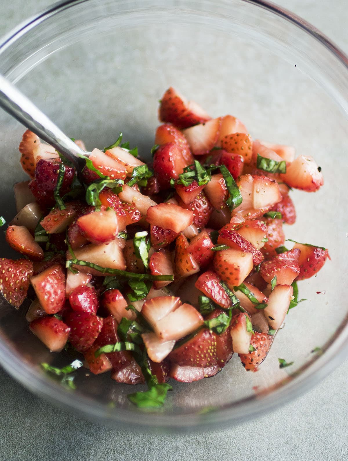 Diced strawberries and chopped basil in a glass mixing bowl.