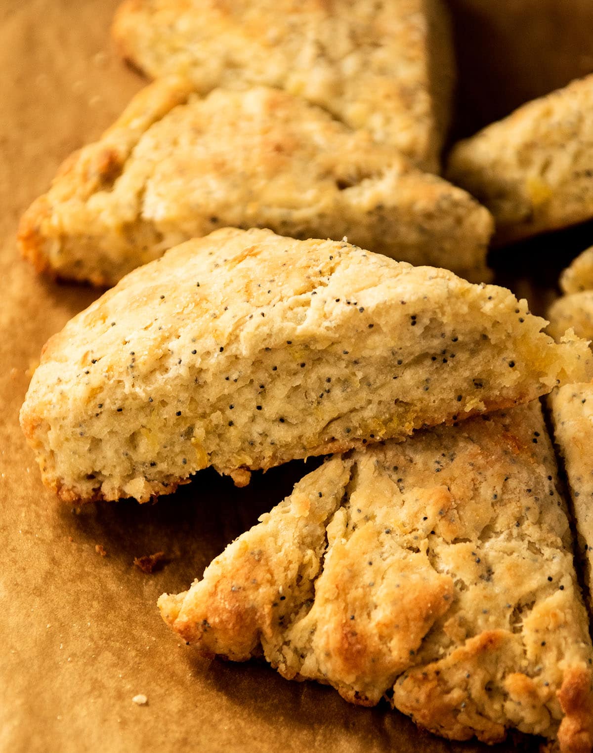 Lemon poppyseed scones stacked on a piece of brown parchment paper.