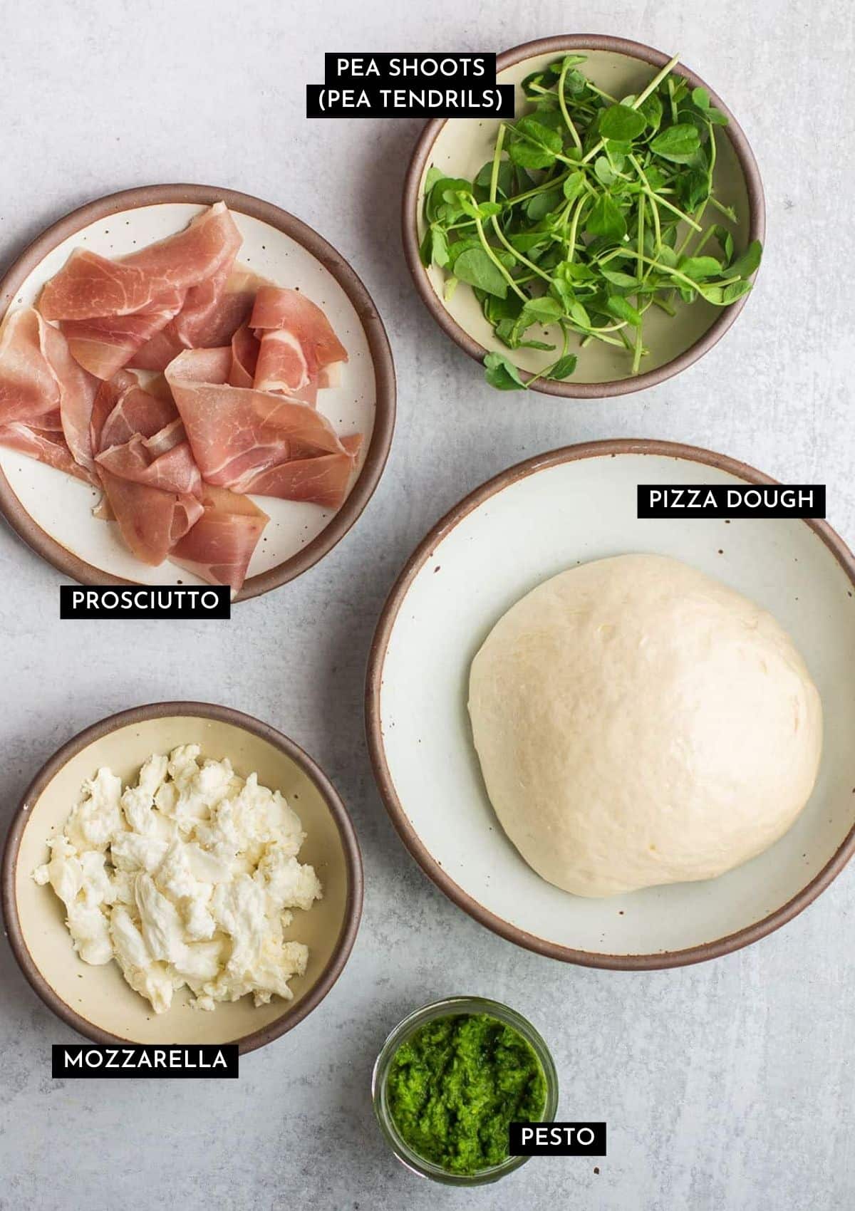 Pizza dough and various toppings, organized into small bowls.