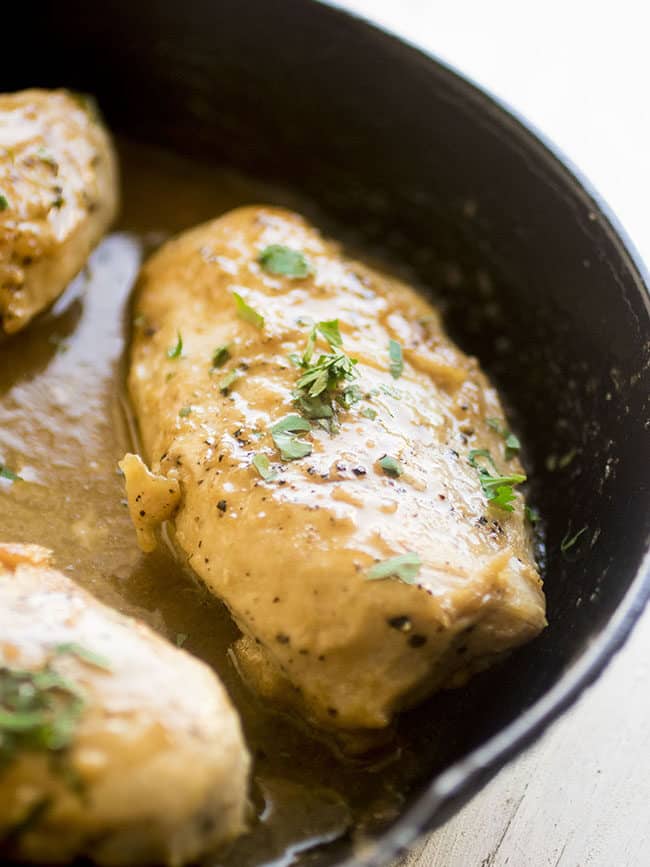 Baked chicken in cast iron pan with mustard sauce and chopped parsley.