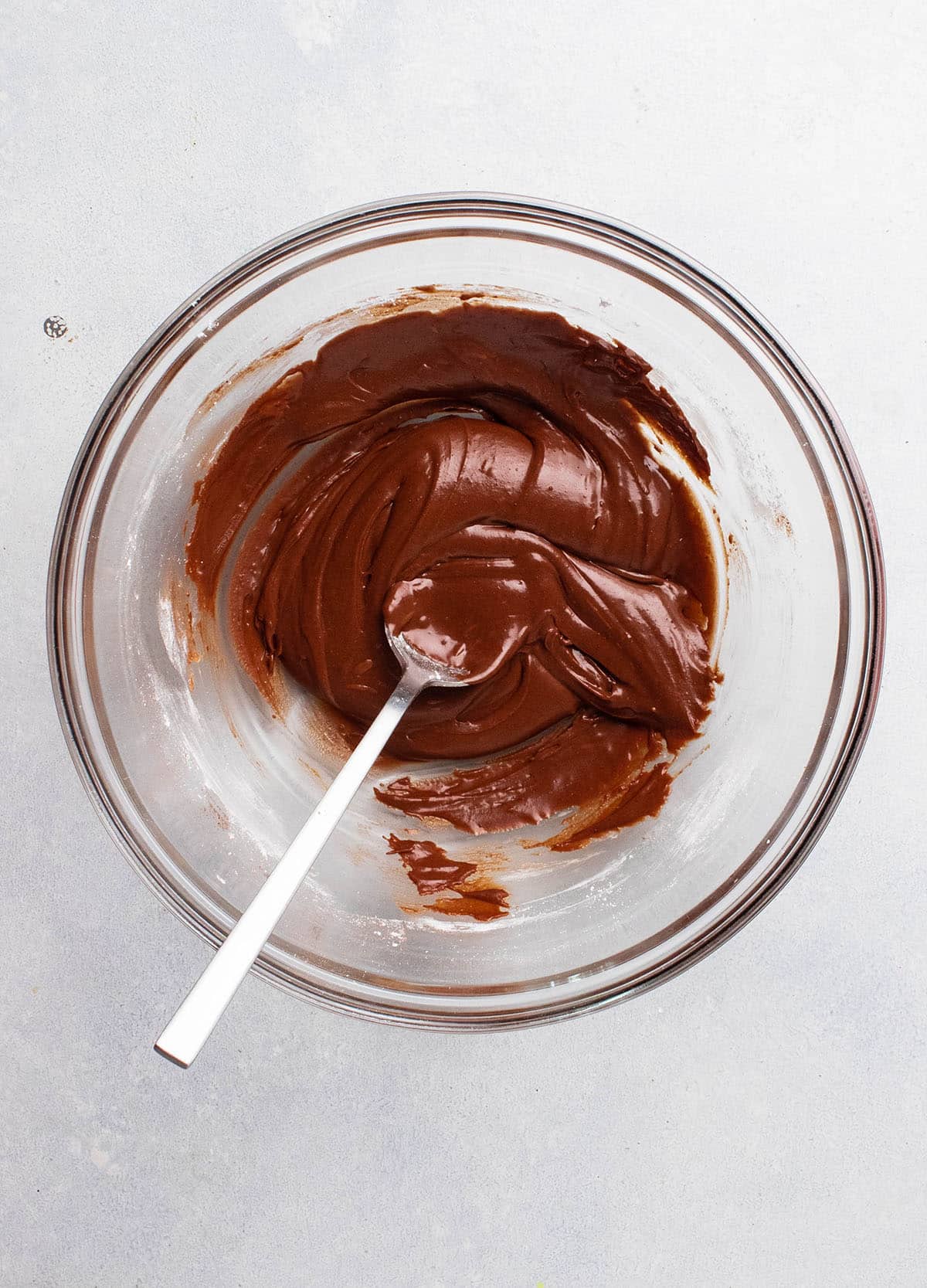 Chocolate fudge frosting in a glass mixing bowl.
