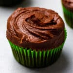 Chocolate cupcake in a green wrapper on a white table.