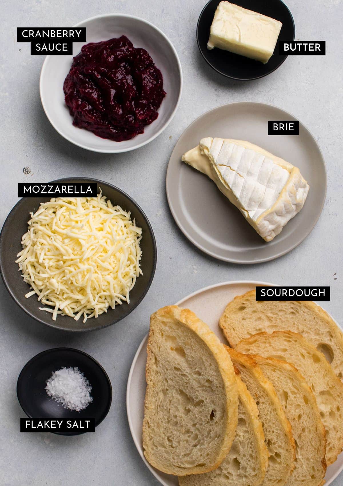 Grilled cheese ingredients, organized into individual bowls on a white table.