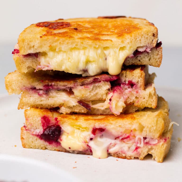 Cranberry grilled cheese sandwiches in a stack on a white plate.