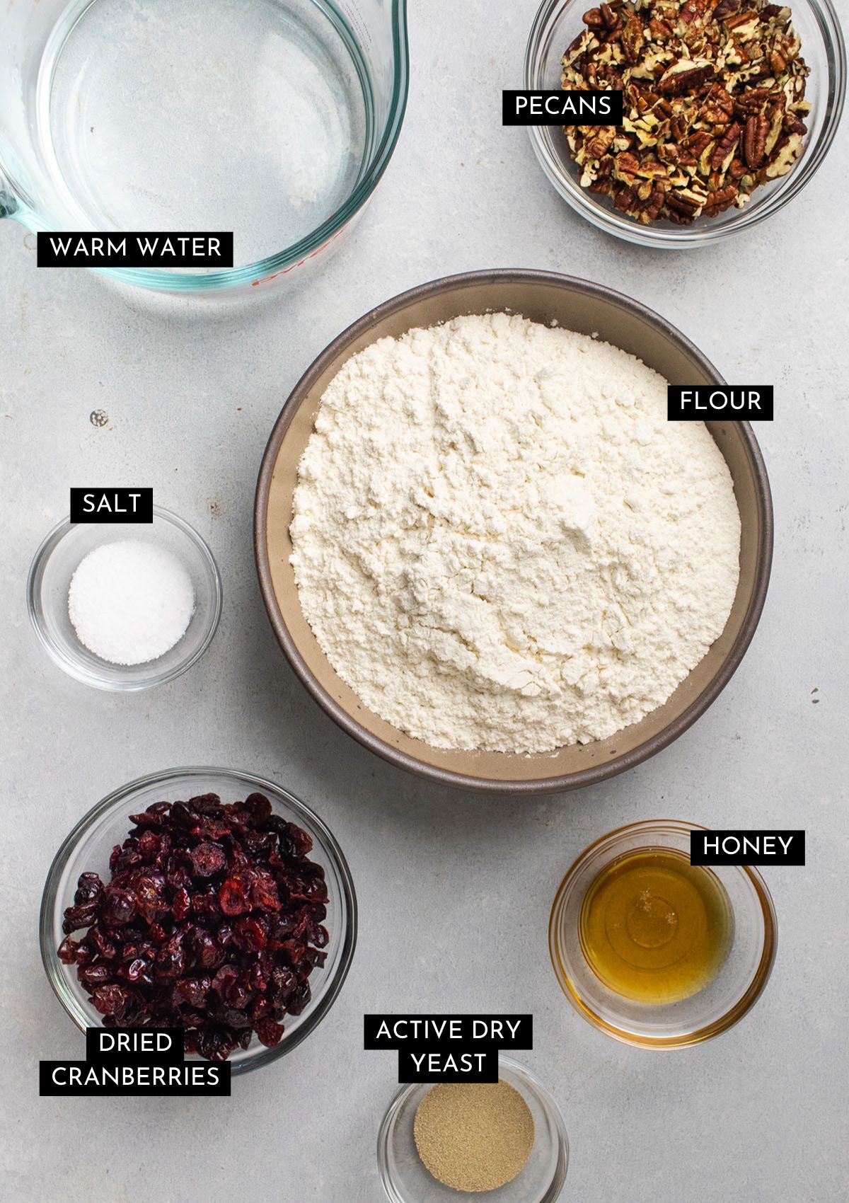 Bread ingredients, organized into individual bowls on a white table.