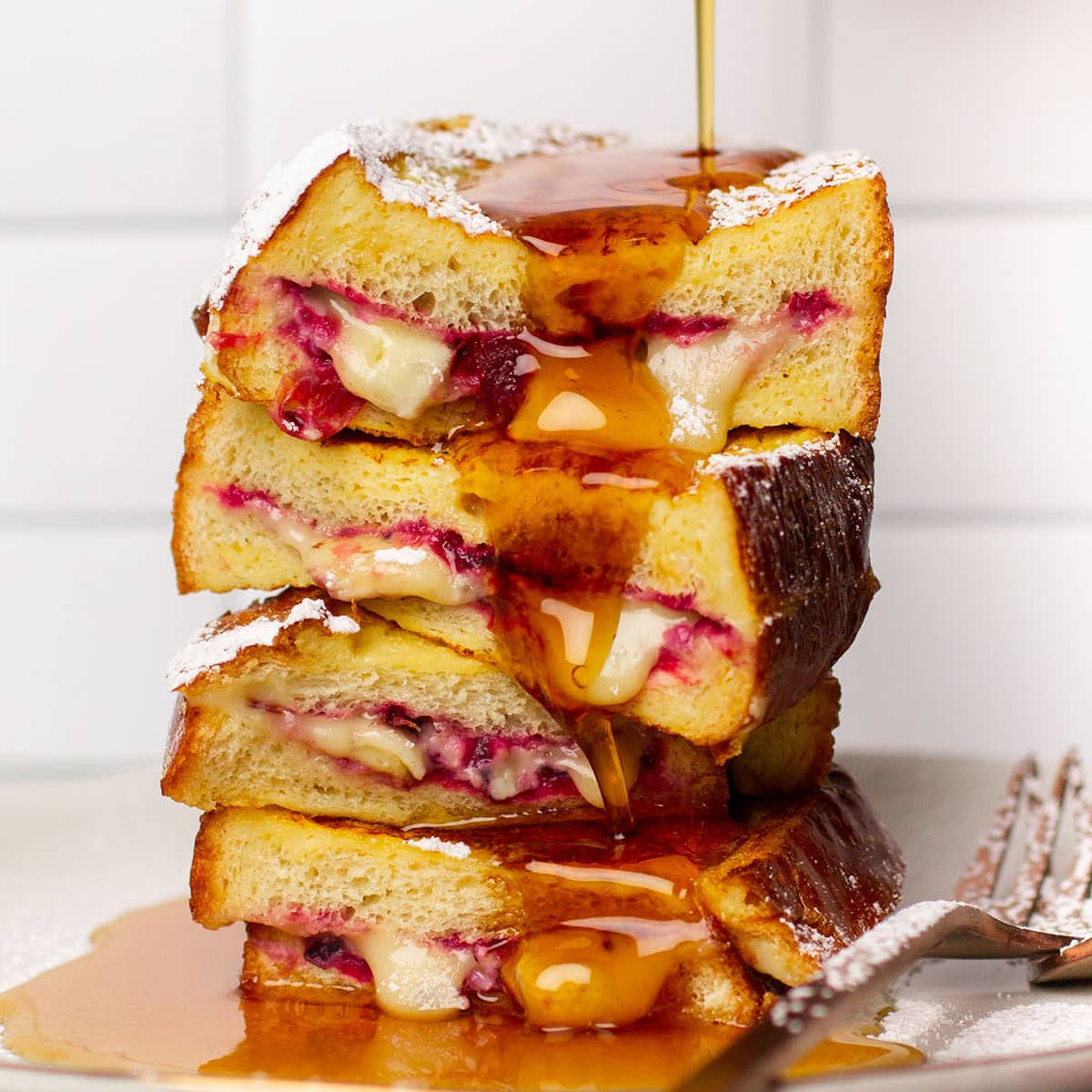 Pouring syrup over a stack of french toast.
