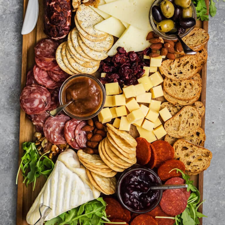 Overhead view of a cheese board with various cheeses, meats, and spreads.