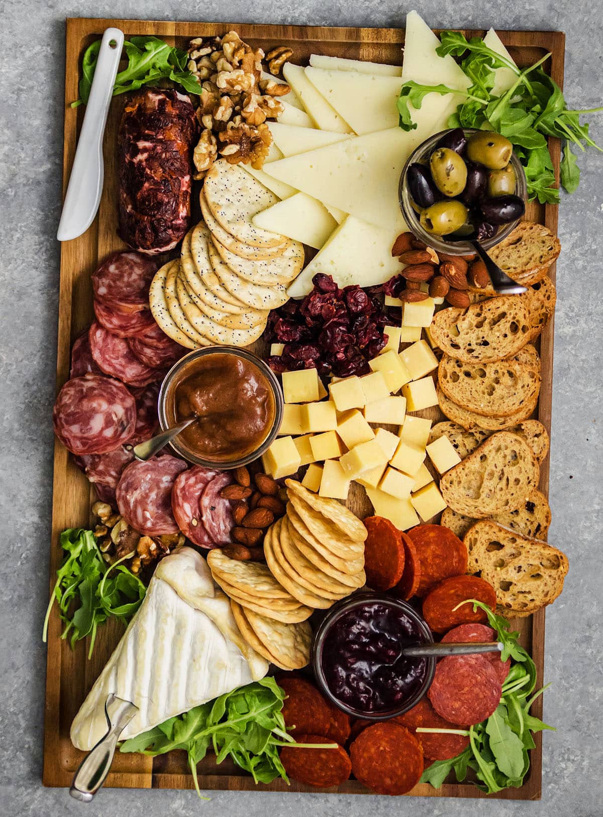 Overhead view of a variety of cheeses arranged on a wood cutting board.