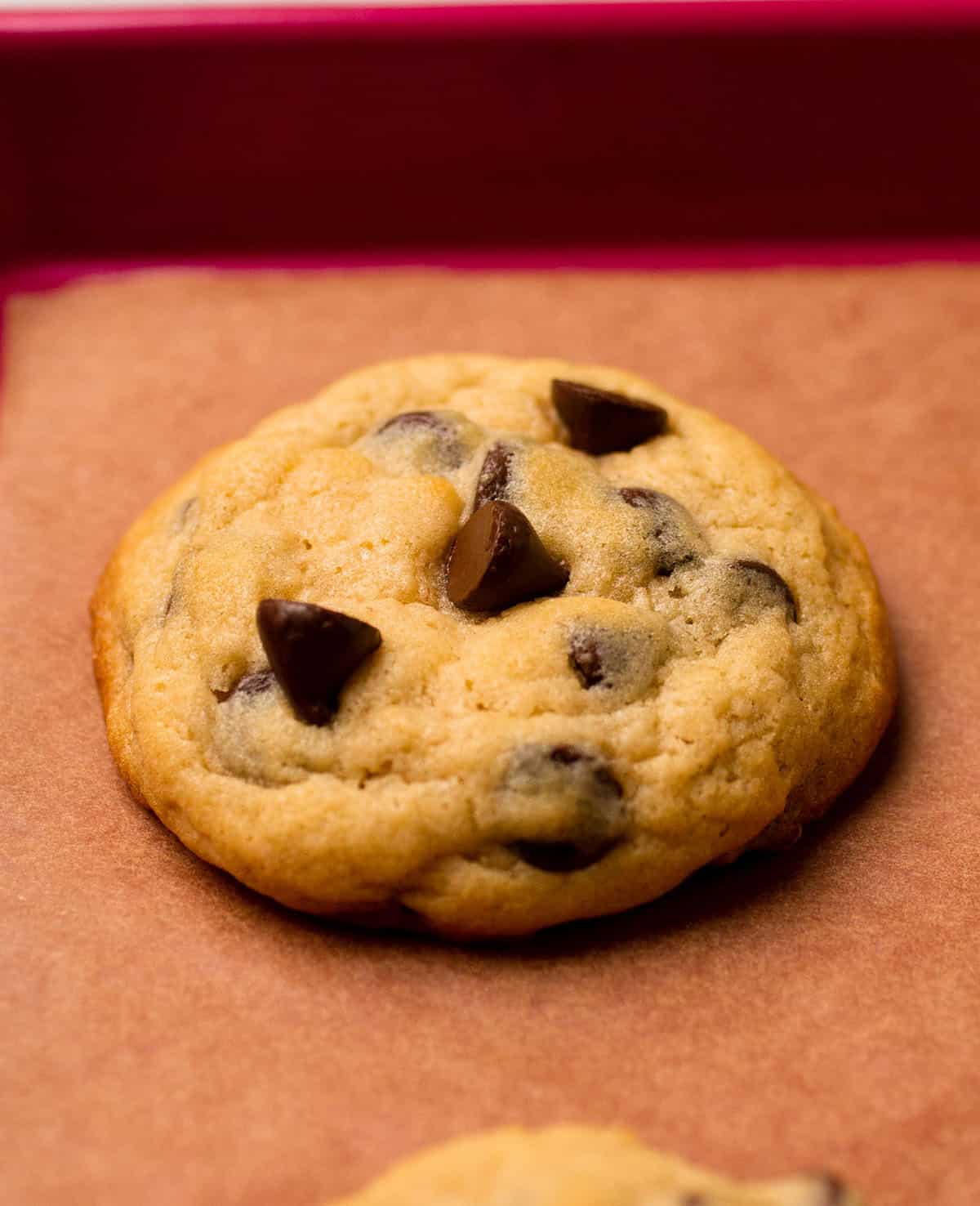 Chocolate chip cookie on a baking sheet lined with parchment.