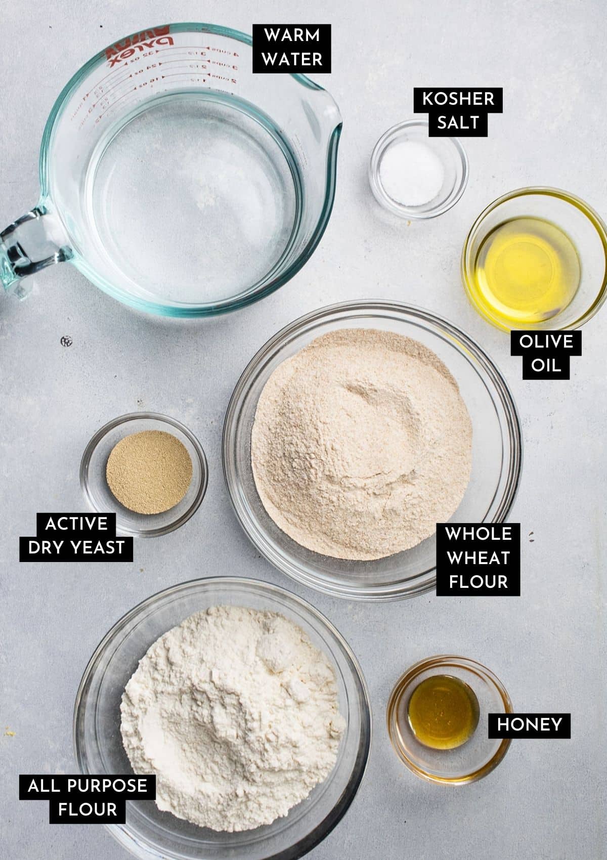 Whole wheat pizza ingredients, organized into individual bowls on a white table.