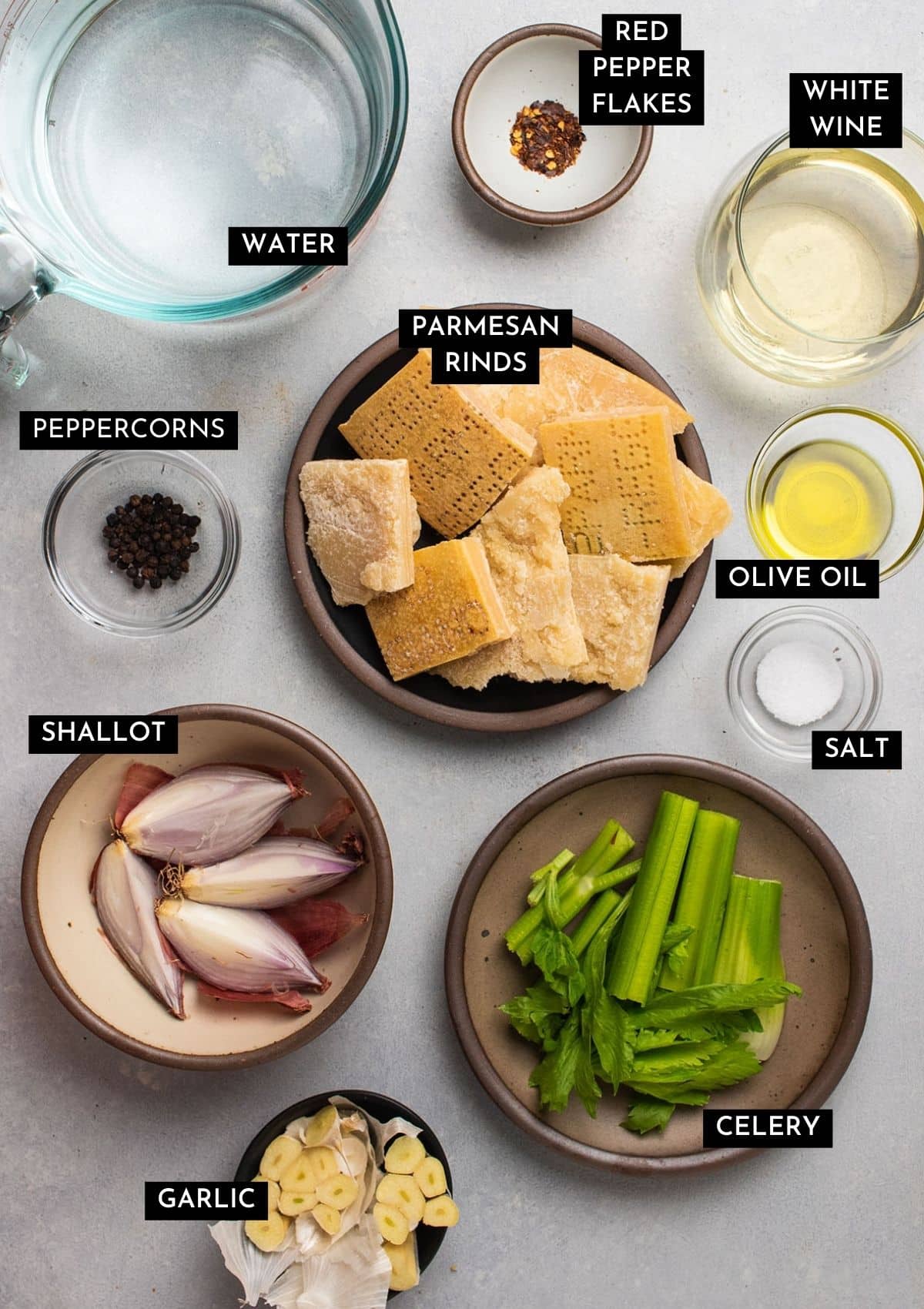Parmesan broth ingredients, organized into individual bowls on a white table.