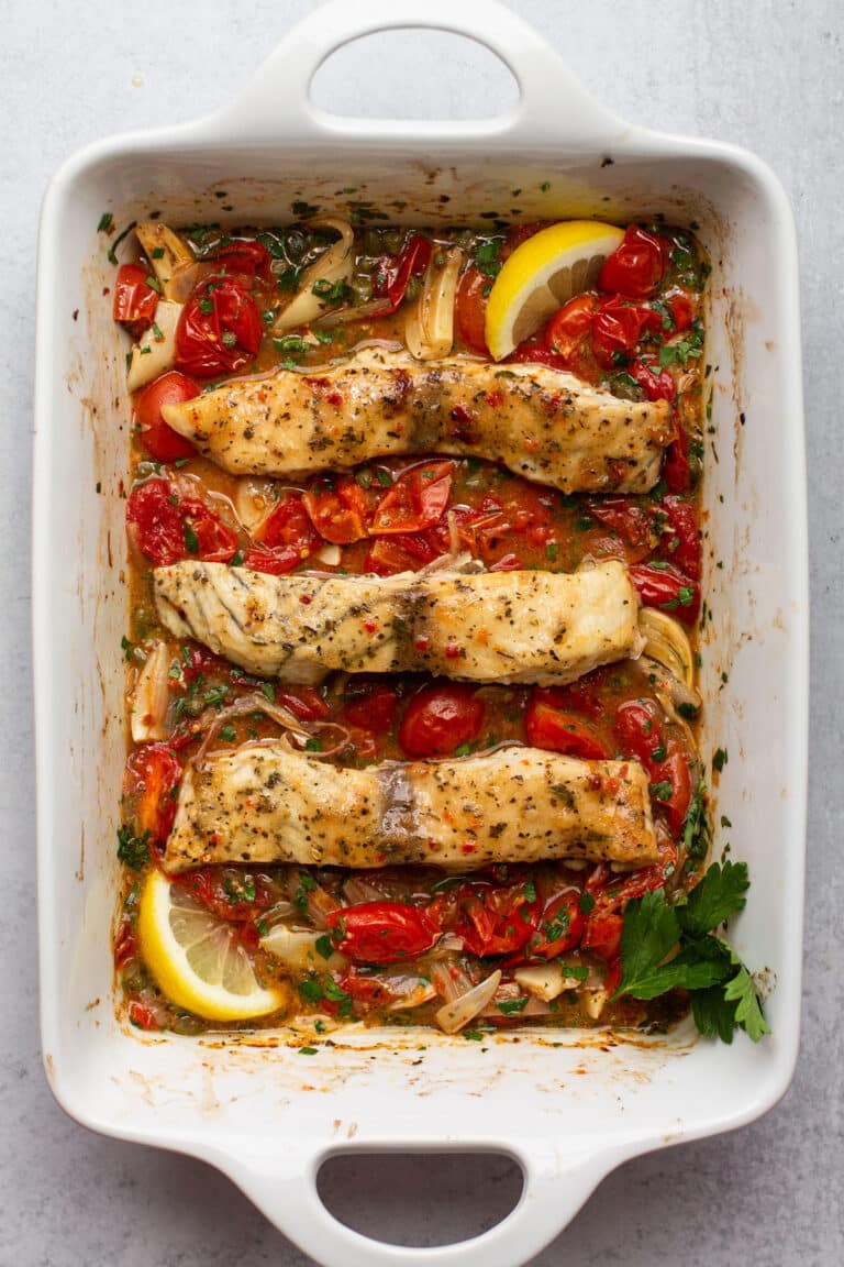 Roasted tomatoes and barramundi in a baking dish.