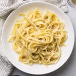 Fettuccine noodles with white sauce in a shallow bowl.