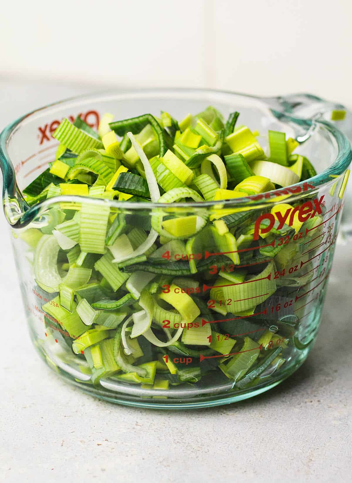 Sliced, cleaned leeks in a large glass measuring cup.