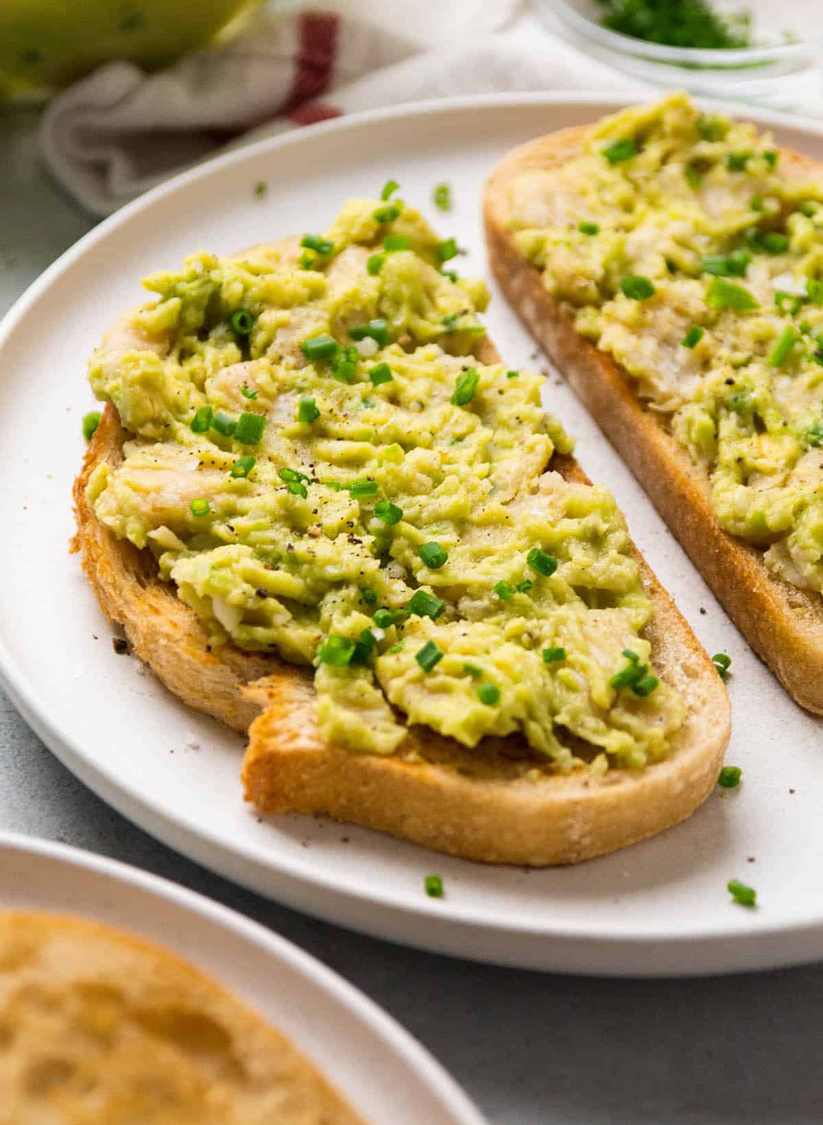 Butter bean avocado toast on a white plate.