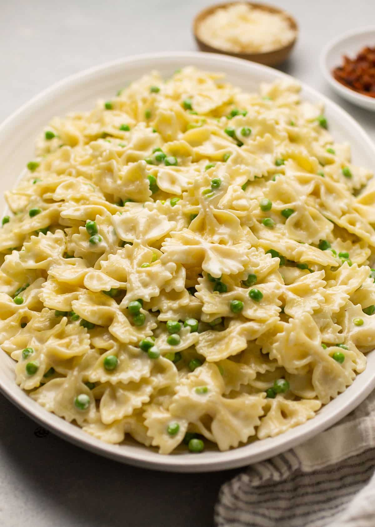 Creamy pasta with peas on a large white serving platter.