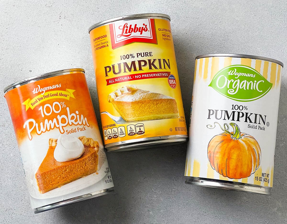 Three cans of pumpkin on a white table.