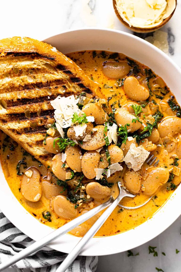 Butter bean stew in a bowl with a piece of grilled bread.