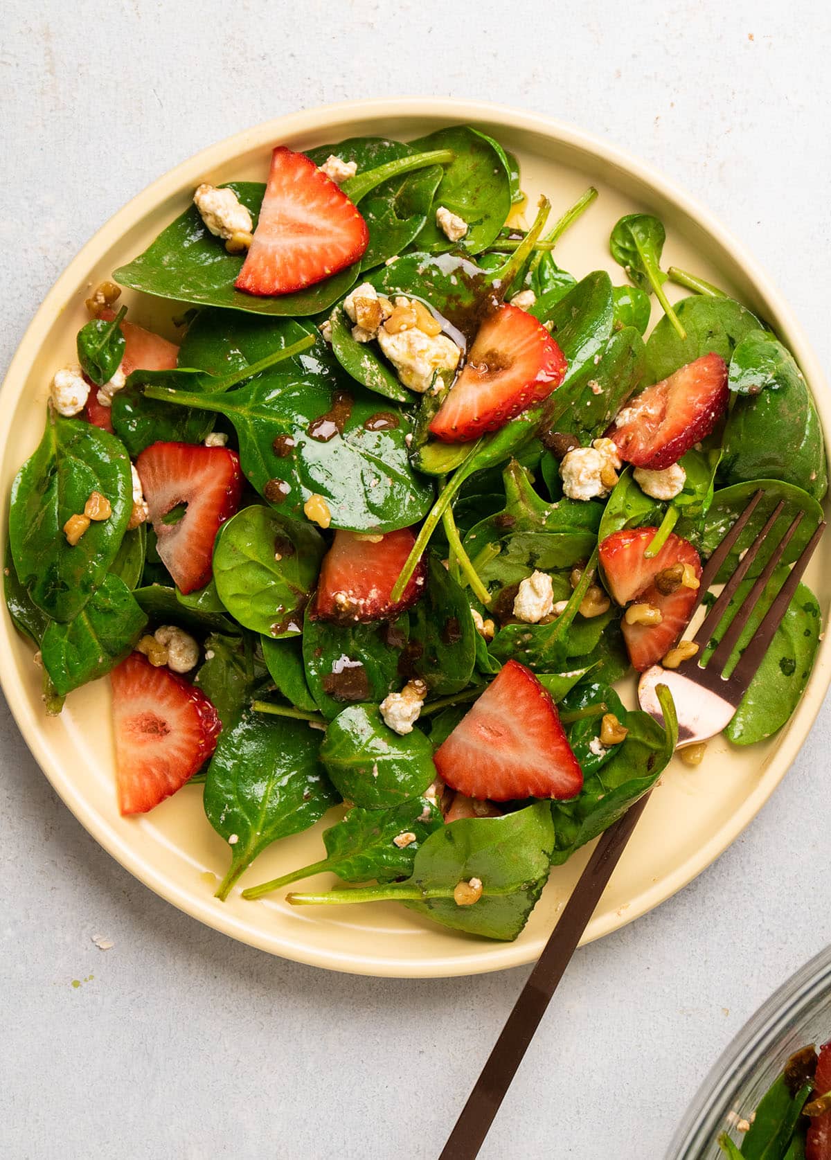 Spinach salad topped with sliced strawberries.
