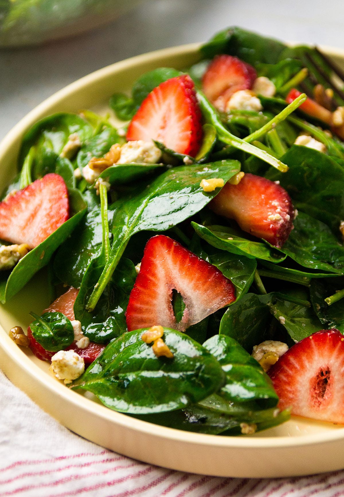 Strawberry spinach salad on a yellow plate.