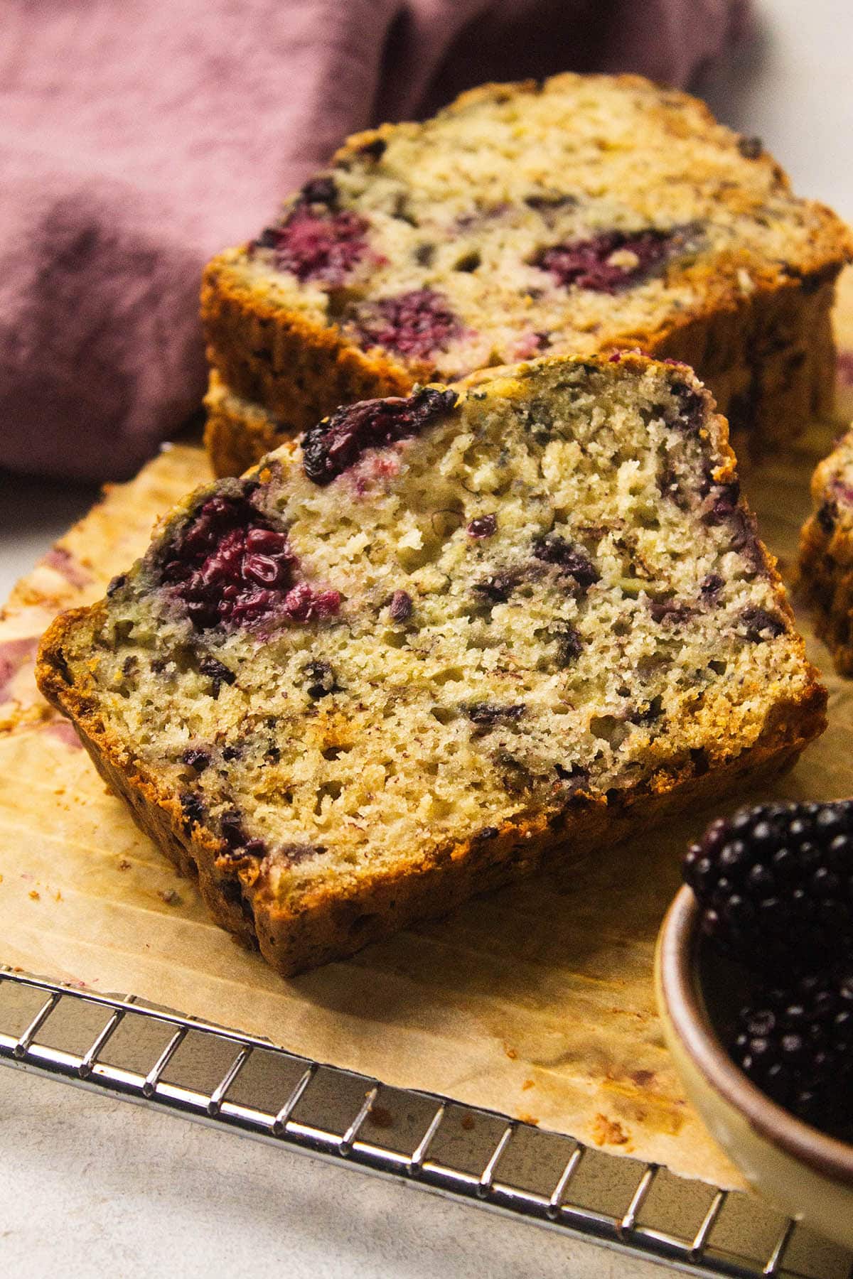 One slice of blackberry banana bread on a cutting board.
