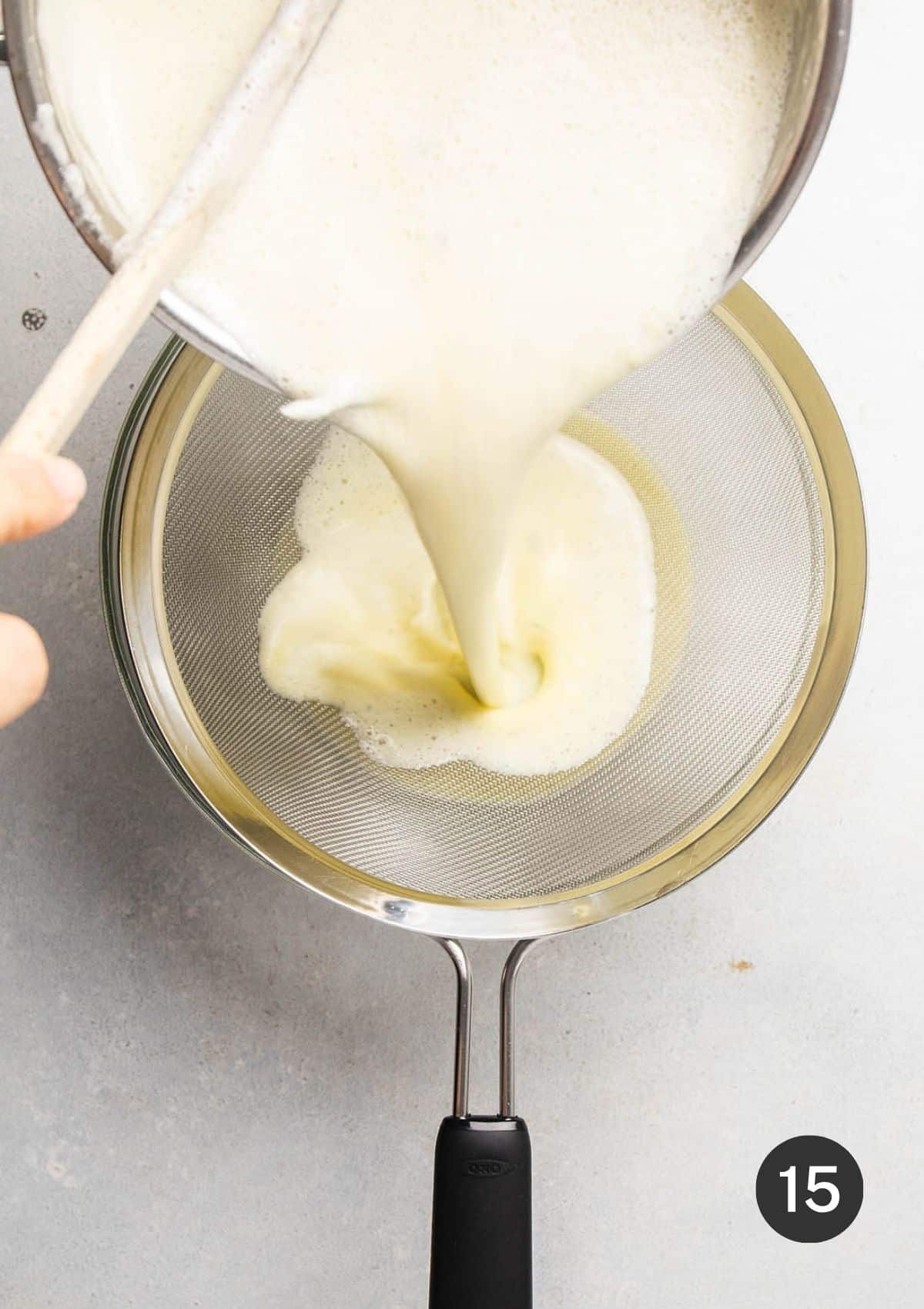 Pouring custard through a mesh sieve.